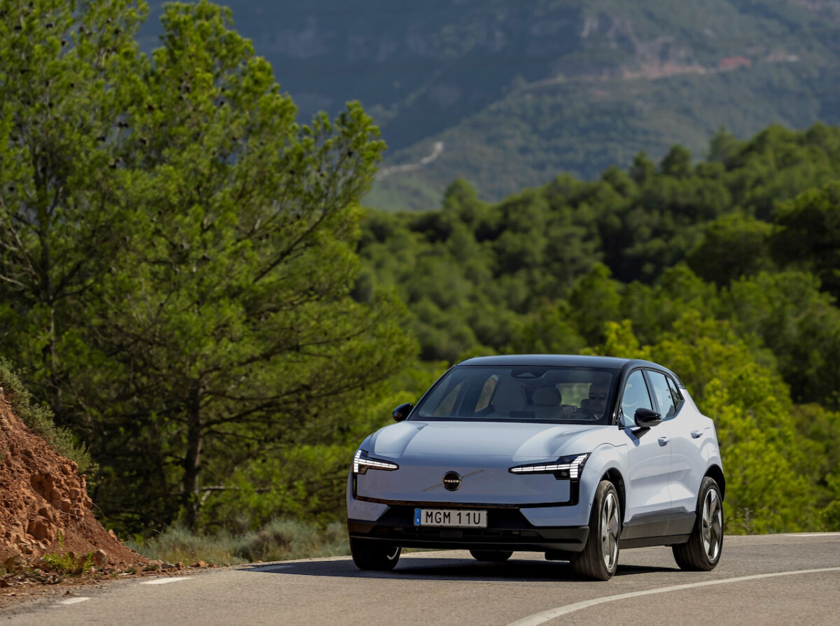 A car driving on the road with trees in the background